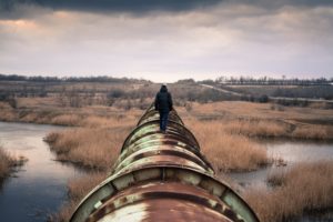 Panoramic look at person walking away from camera while standing on pipeline