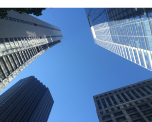 Looking up at clear blue sky while surround by skyscrapers