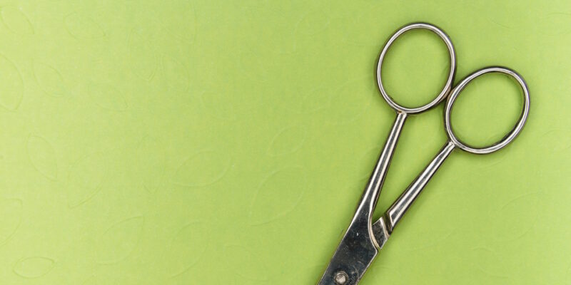 Silver scissors on lime green background